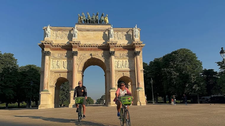 Cyclists at the Arc de Triomphe du Carrousel in Paris at sunrise, before the crowds